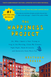 Cover of "The Happiness Project," featuring brown buildings with blue sky above them and the title in yellow text on the sky