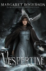 Cover of the book, featuring a girl with long dark hair wearing a gray dress and a dark brown cloak. she has a jeweled box around her neck, a dagger in one hand, and a handful of silver mist in the other. Behind her is a dark forest with a flock of crows, one of whom is white.